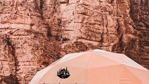 A geodesic dome tent labeled 'Rum mars luxury sands camp' with a view of rocky cliffs in the background. - Rum mars sands luxury camp (Wadi Rum)