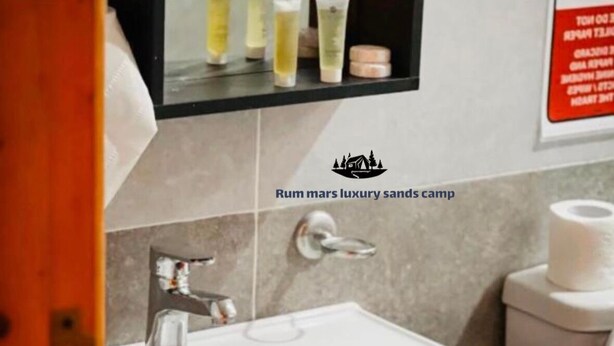A bathroom with a white sink, a mirror, and toiletries on the wall. - Rum mars sands luxury camp (Wadi Rum)