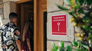 Een bord met de tekst 'Alojamientos extrahoteleros' en 'Apartamentos turísticos' op een stenen muur.