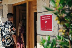 A sign indicating 'Alojamientos extrahoteleros' and 'Apartamentos turísticos' on a stone wall. - Accessible Apartment with Terrace & Garden View (Rasines)