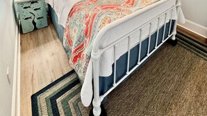 Ein Schlafzimmer mit einem Bett, einem Nachttisch, einem Deckenventilator und einem Fenster mit Vorhängen.