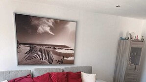 Un soggiorno moderno con un divano grigio, cuscini rossi, un tavolino in legno e un grande quadro astratto appeso alla parete.