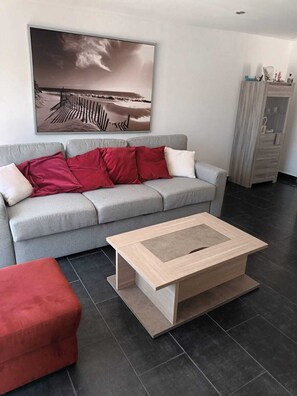 A modern living room with a grey sofa, red cushions, a wooden coffee table, and a large abstract painting on the wall. - Provençal and Mediterranean house 167 sqm (Marseille)
