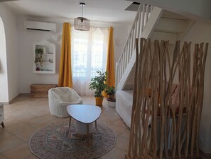 A room with a white chair, a small table, a potted plant, a staircase, and a decorative screen. - Provençal and Mediterranean house 167 sqm (Marseille)