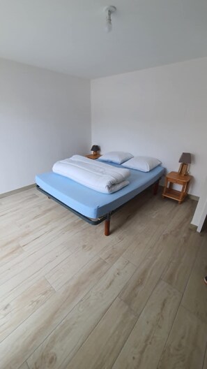 Un dormitorio con una cama, dos mesitas de noche y suelo de madera.