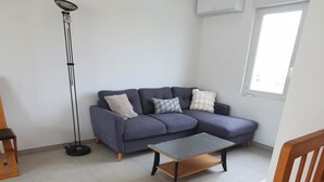 A living room with a sofa, a coffee table, a floor lamp, and a window. - Charm & Relaxation : Family home with heated pool (Jard-sur-Mer)