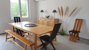 A dining area with a wooden table, benches, chairs, a window, and a cabinet. - Charm & Relaxation : Family home with heated pool (Jard-sur-Mer)