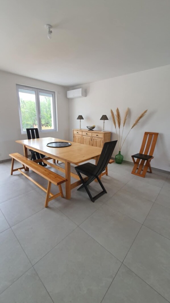 A dining area with a wooden table, benches, chairs, a window, and a cabinet.