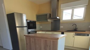 A kitchen with a central island, stainless steel appliances, and a window above the sink. - Charm & Relaxation : Family home with heated pool (Jard-sur-Mer)