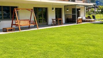 Une maison moderne dotée d’une pelouse bien entretenue, d’un espace extérieur aménagé pour se détendre et d’un balcon offrant une vue agréable.