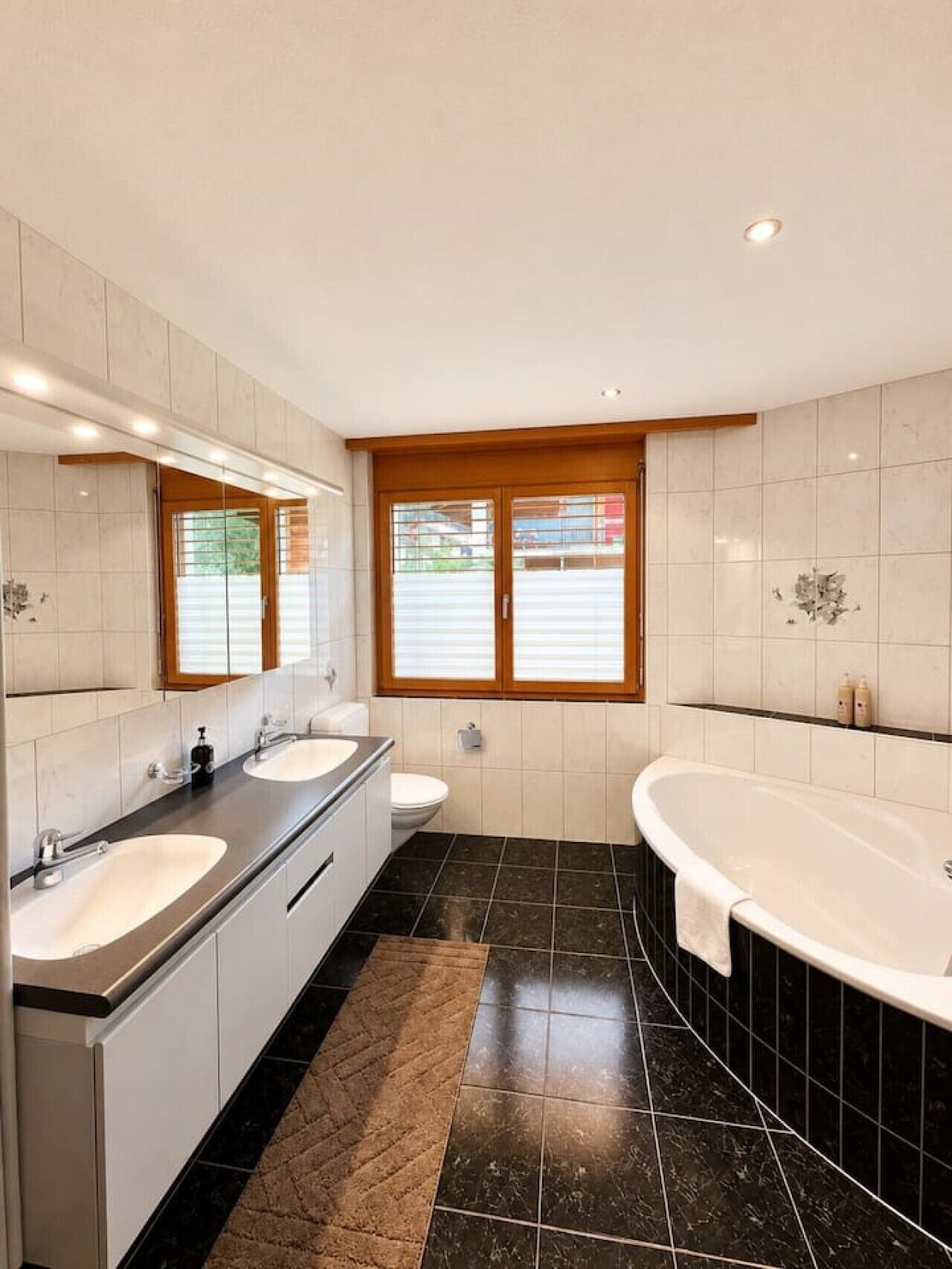 Une salle de bain moderne avec deux lavabos, des toilettes et une baignoire.