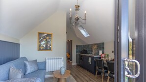 A modern living room with a sofa, a coffee table, and a dining area with chairs. - Narrow Water Lodges (Dundalk)