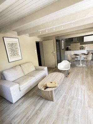 A modern living room with a sofa, a coffee table, and a dining area with chairs. - New - Private Garden - Near Aix Centre (Aix-en-Provence)