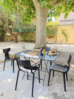 Een terras met een tafel, stoelen en een fles RICAR.