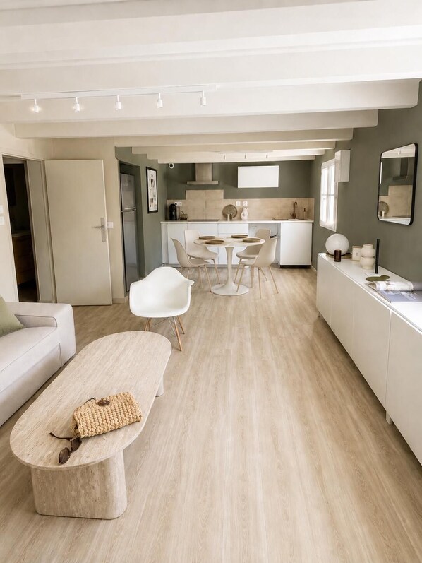 Un salon moderne comprenant un canapé, une table basse et un coin repas avec des chaises et une table.