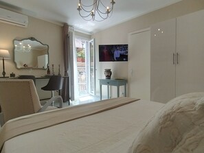 Een hotelkamer met een bed, een bureau, een stoel, een televisie en een kledingkast.