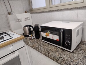 A kitchen with a gas stove, a kettle, a microwave, and a toaster. - Vrbo Property (Modica)