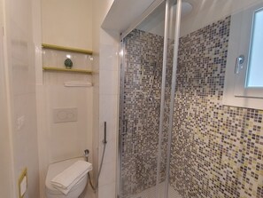Een badkamer met een douche, toilet en een plankje met een decoratief object.