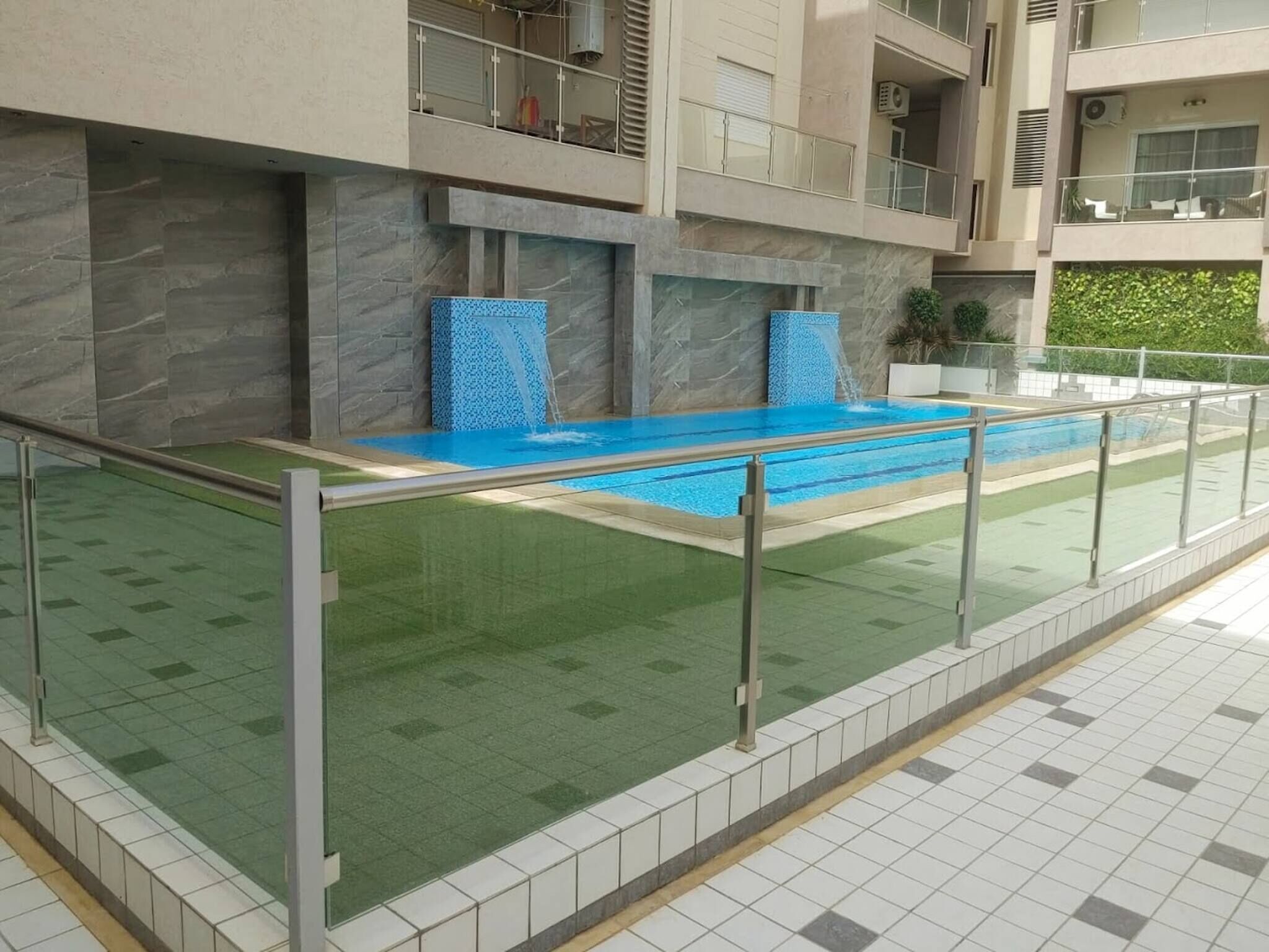 Une piscine dotée d’une paroi en verre, d’un mur en pierre et d’un sol carrelé.