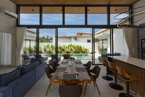 Ein moderner Essbereich mit Blick auf einen Pool, eine Bar und ein großes Fenster.