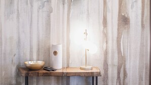 Ett rum med ett träbord, en vit lampa och en rund pall placerad mot en vägg med en tydlig struktur.