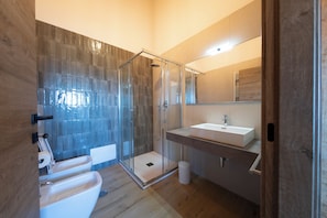 A modern bathroom with a glass-enclosed shower, a sink, and a mirror.