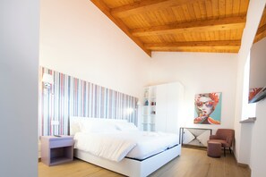 A modern bedroom with a bed, a nightstand, a chair, a shelf unit, and a painting on the wall. - Farmhouse nestled in the countryside on the outskirts of Rome. (Lazio)