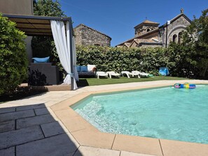 Ein Pool mit Liegestühlen und einer überdachten Sitzgelegenheit.