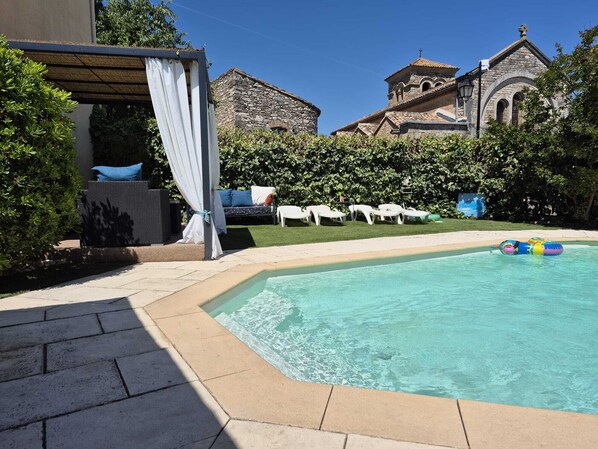 Ein Pool mit Liegestühlen und einer überdachten Sitzgelegenheit.