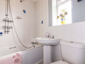 A bathroom with a bathtub, a sink, and a toilet. There is a showerhead and a towel rack. - Treetops (Par)