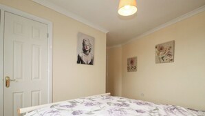 Une chambre à coucher avec un lit, une porte et deux tableaux accrochés au mur.