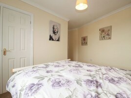 Un dormitorio con una cama, una puerta y dos cuadros en la pared.