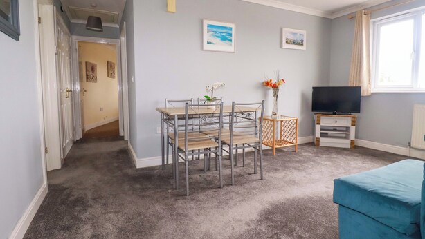 Un salon comprenant une table à manger, des chaises, un téléviseur et un canapé.