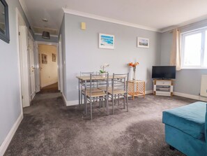 A living room with a dining table, chairs, a TV, and a sofa. - Treetops (Par)