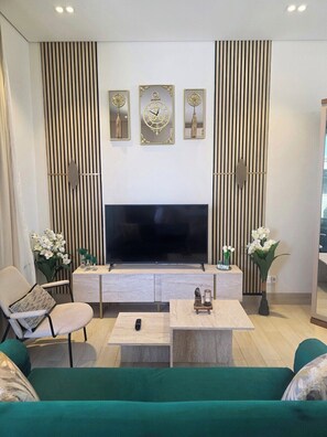 Ein Wohnzimmer mit Flachbildfernseher, einer Couch, einem Couchtisch und Dekorationselementen.