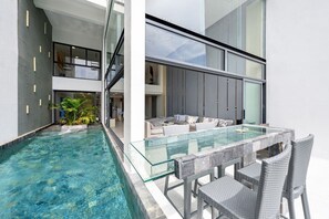 A modern indoor pool with glass barriers, a seating area with a sofa and chairs, and a view of the interior space. - Master Peak Villa (J3) 5-bedrooms Near Beach (Tambon Bo Put)