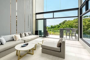 A modern living room with a sofa, coffee table, and a balcony with outdoor seating. - Master Peak Villa (J3) 5-bedrooms Near Beach (Tambon Bo Put)