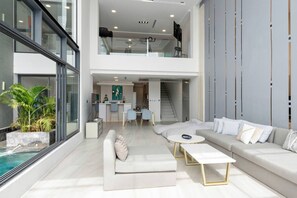 A spacious living area with a sofa, coffee table, and a dining area with chairs and a kitchen in the background. - Master Peak Villa (J3) 5-bedrooms Near Beach (Tambon Bo Put)