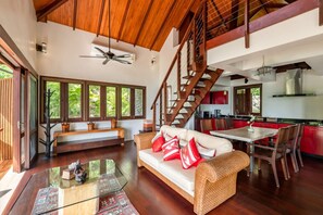 A spacious living area with a high ceiling, a staircase, a dining area, and a kitchen. - Villa Sunset Rock by MPS (Na Mueang)