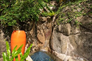 A rock garden with a small water feature, a stone wall, and a metal railing. - Villa Sunset Rock by MPS (Na Mueang)