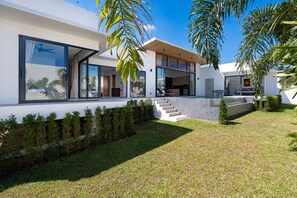 Ein modernes Haus mit großem Panoramafenster, einer Betonstiege und einem gepflegten Rasen.
