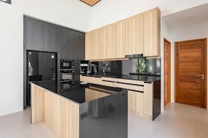 Eine moderne Küche mit schwarzen Arbeitsplatten, Holzschränken und einem eingebauten Backofen.