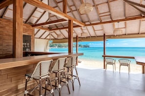 Eine Strandbar mit Holzmöbeln und Blick auf den Ozean.