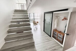 Ein modernes Interieur mit einer Holztreppe, einem Schiebetürenschrank und einer minimalistischen Sitzgruppe.
