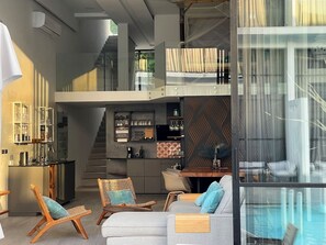 Ein modernes Interieur mit Küche, Essbereich und einem Pool mit Glasverkleidung.