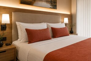 Ein Hotelzimmer mit einem großen Bett, zwei Nachttischlampen, einem Nachttisch und einem Gemälde an der Wand.