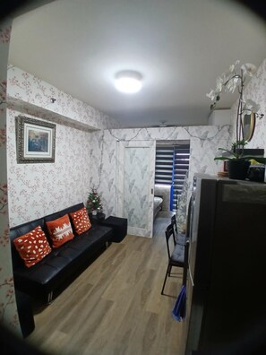 A living area with a sofa, a small Christmas tree, and a television. - Family Condo SMB Live,Love & Laugh & have Fun (Pasay City)
