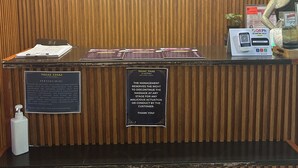 Vastaanottotiski, jossa on puupaneelista tehty koristelu, kyltti, jossa lukee ”Nuat Thai Foot & Body Massage”, patsas ja QR-koodi, jonka voi skannata mobiililaitteella.