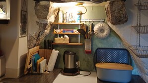 A kitchen with a stone wall, wooden shelves, a Siemens appliance, and various kitchen utensils. - Welcome to our charming, authentic stone house on the island of Krk. (Kornić)