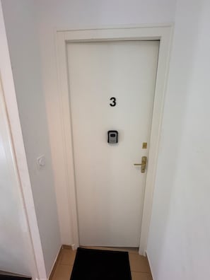 Una porta bianca con il numero 3, un campanello e una maniglia.